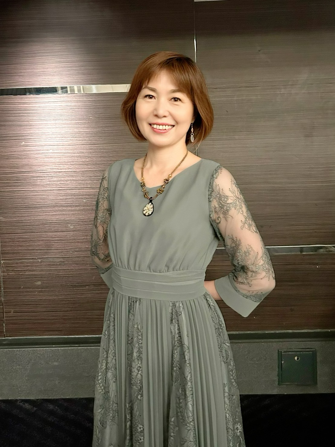 グレーのレースドレスを着た千原輝子 - エレガントな微笑み