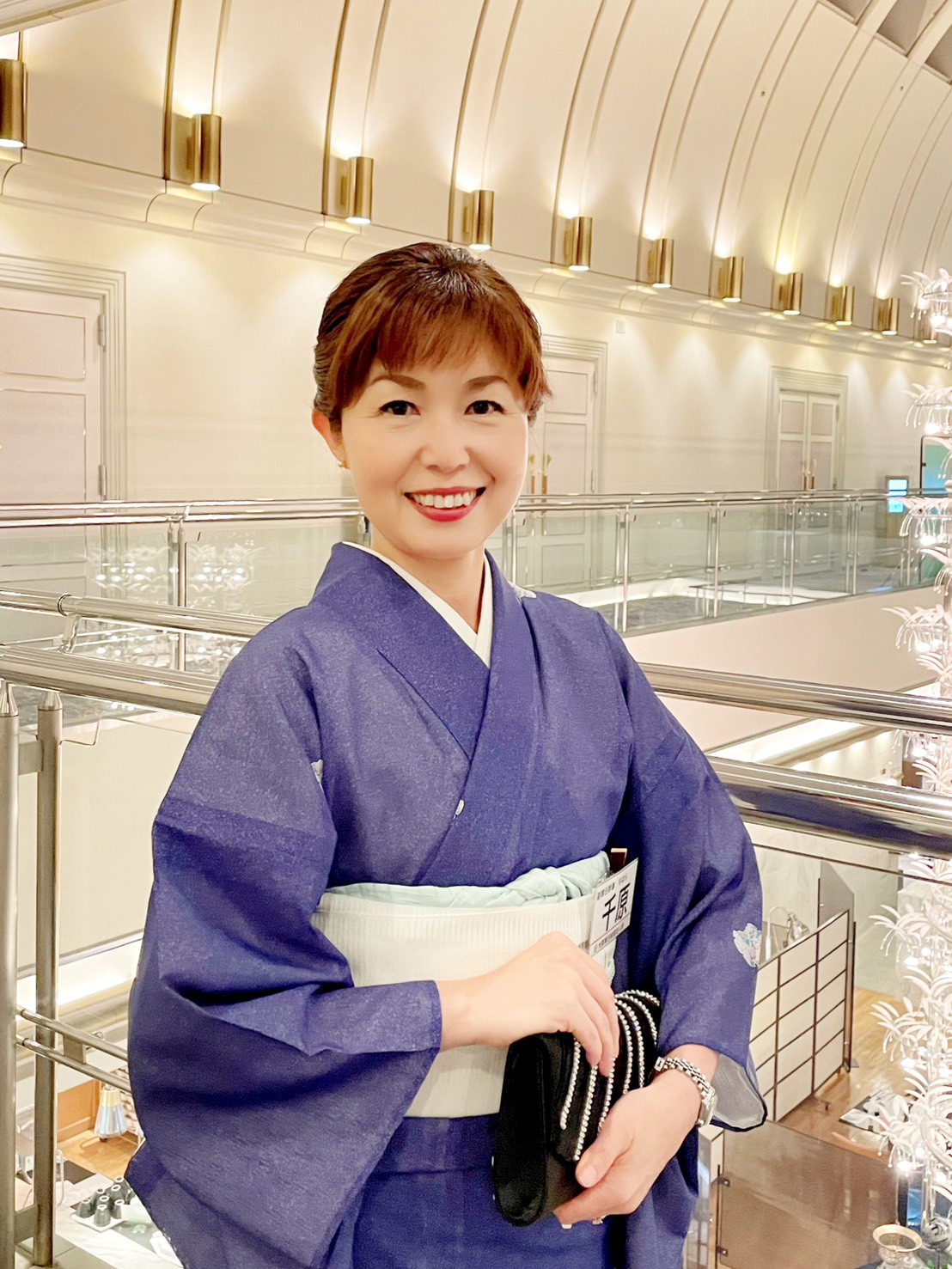 青紫の着物を着て品格のある立ち姿の千原輝子