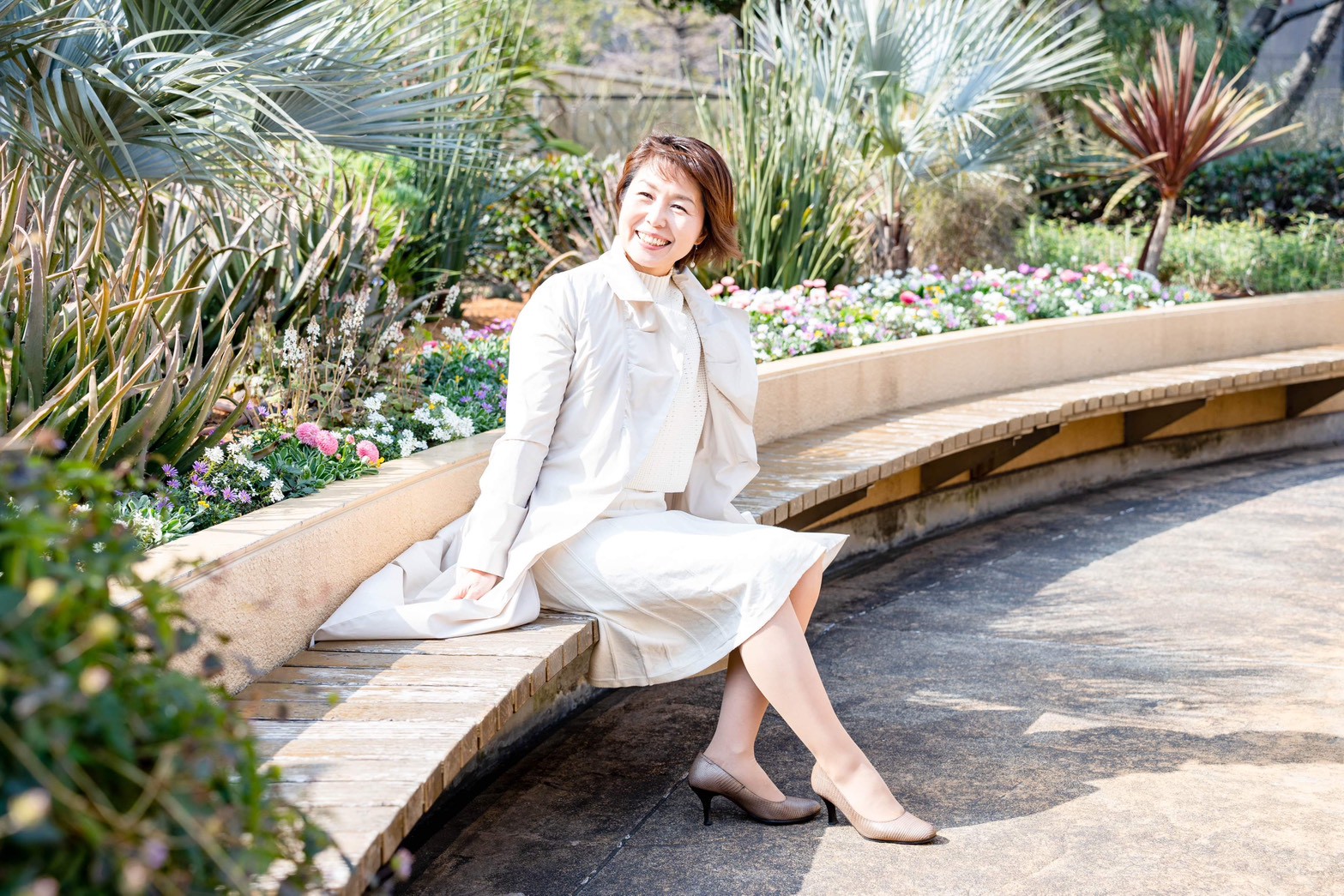 庭園のベンチに座り、温かい笑顔を見せる千原輝子